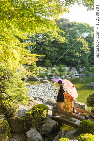 A symbol of Japanese beauty: A bride and groom in traditional Japanese attire walking side by side through a gorgeous, beautiful Japanese garden. High-quality Japanese wedding bridal materials. 132589901