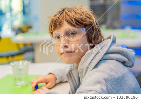 Teenage boy wearing safety glasses prepares to conduct chemistry experiments, representing STEM education, curiosity, and the excitement of hands-on scientific discovery 132590180