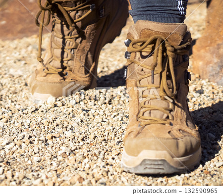 Legs in hiking boots closeup, a girl walks on a rocky desert terrain. Legs in hiking boots closeup, a girl walks on a rocky desert terrain. 132590965