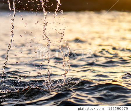 Drops of water fallling to the ocean at sunset closeup. 132590979