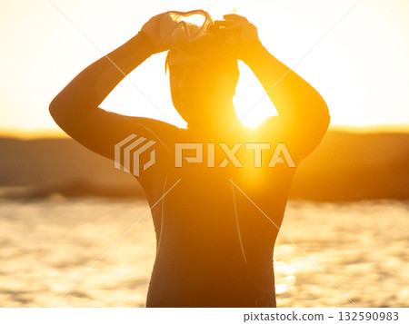 A man is preparing for diving in the ocean at sunset. 132590983