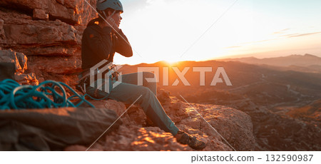 Young girl is preparing for training on the rocks sunset, in the mountains and puts a helmet 132590987