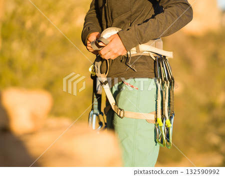A woman looks at a beautiful red rock and takes magnesia in her hand, getting ready for training and climbing. 132590992
