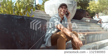 A young happy man talks, communicates on a smart phone outdoors. 132590993