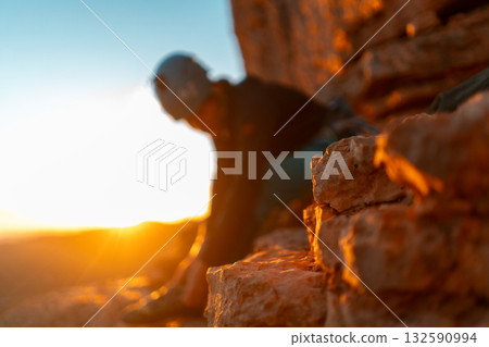 Young girl is preparing for training on the rocks sunset, in the mountains and puts a helmet 132590994