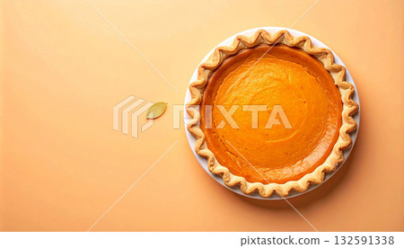 An overhead shot of a single, whole pumpkin pie on a minimal orange background with copy space. 132591338