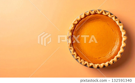 An overhead shot of a single, whole pumpkin pie on a minimal orange background with copy space. 132591340