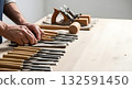 Carpenters hands selecting a chisel from a large set of woodworking tools on a workbench. Carpenters hands selecting a chisel from a large set of woodworking tools on a workbench. 132591450