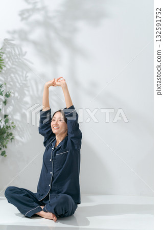 A woman in pajamas stretching 132591752
