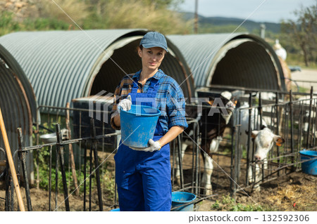 Adult woman with bucket at pen with calves Adult woman with bucket at pen with calves 132592306