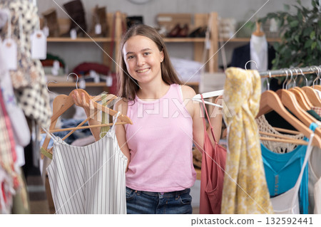 Teenage girl choosing top in clothing store Teenage girl choosing top in clothing store 132592441