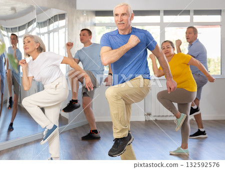 Positive senior man practicing Tai Chi with group of aged people Positive senior man practicing Tai Chi with group of aged people 132592576