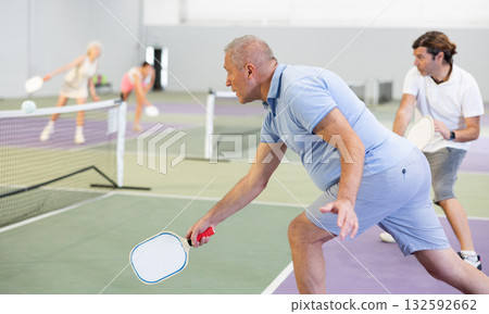 Sporty senior man playing pickleball on indoor court 132592662
