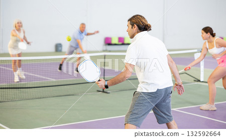 Rear view of man in sportswear playing pickleball tennis on court. Racket sport training 132592664