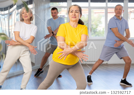 Cheerful elderly woman learning dynamic dances at group choreography lesson Cheerful elderly woman learning dynamic dances at group choreography lesson 132592717