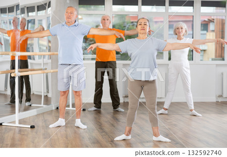 Positive mature woman practicing ballet positions standing in row with others Positive mature woman practicing ballet positions standing in row with others 132592740