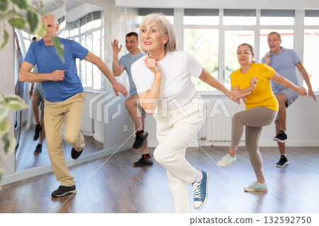 Woman participating in Zumba class for seniors in fitness studio Woman participating in Zumba class for seniors in fitness studio 132592750