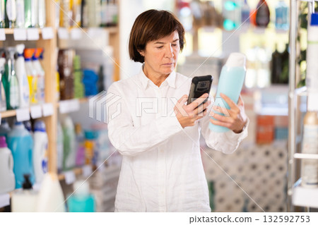 Checking expiration date of shampoo or shower gel - female shopper scans QR code on label of shampoo using smartphone 132592753
