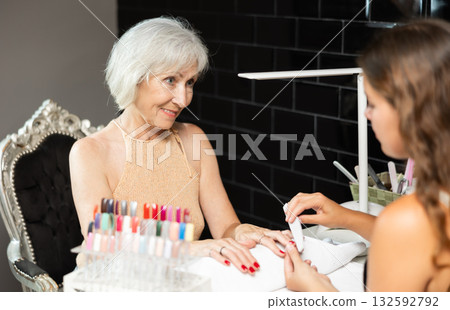 Unrecognizable girl manicure master files nails and performs grooming procedure for senior woman Unrecognizable girl manicure master files nails and performs grooming procedure for senior woman 132592792
