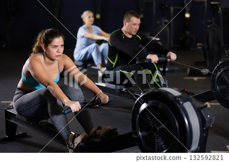 Sporty young woman using cable row machine in gym 132592821