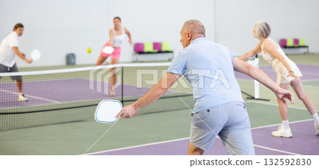 Rear view of man in sportswear playing pickleball tennis on court. Racket sport training 132592830