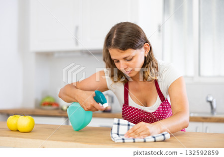 Young woman cleaning kitchen countertop at home 132592859