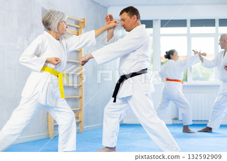 Group of mature people in kimono sparring together in gym during karate training 132592909