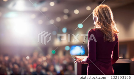 Female speaker presenting at a conference with audience engaged in a professional setting Female speaker presenting at a conference with audience engaged in a professional setting 132593196