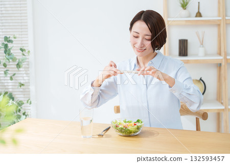 Woman eating salad and smartphone Woman eating salad and smartphone 132593457