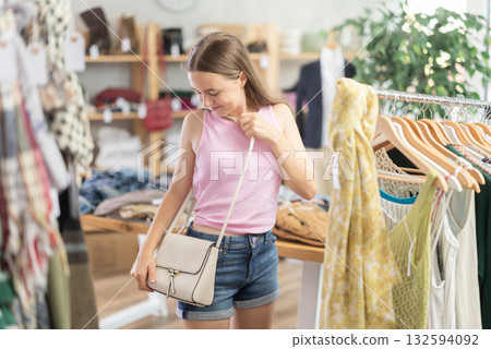 Young teen girl shopping - choosing a fashionable handbag in clothing store 132594092
