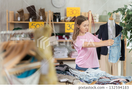 Teenager chooses jeans on sale 132594183
