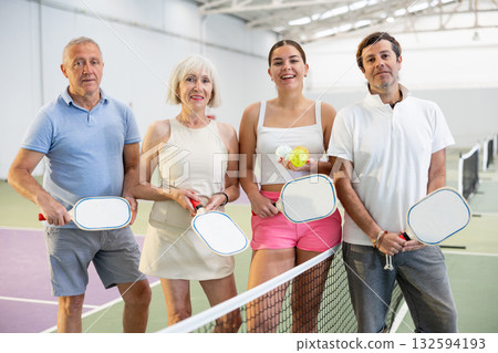 Smiling pickleball players with rackets and balls posing on court Smiling pickleball players with rackets and balls posing on court 132594193