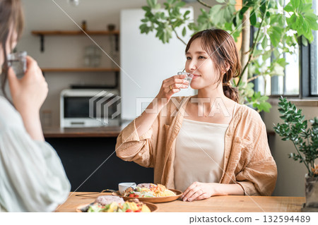 Young Asian woman drinking sake from a chilled glass at a girls' party 132594489