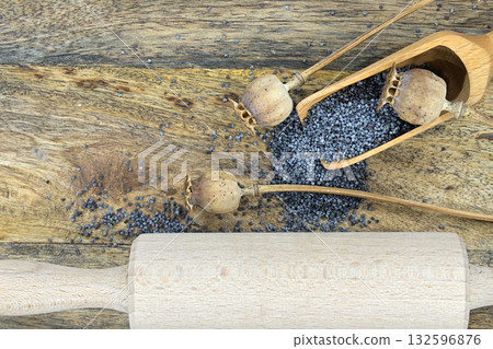 Poppy seeds and several dried poppy seed pods on wooden table 132596876