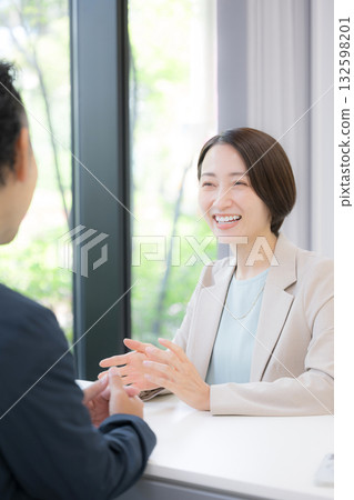 兩位商人,一男一女,正在辦公室進行商務會談;一位身著套裝的女士正在推銷保險和規劃服務。 兩位商人,一男一女,正在辦公室進行商務會談;一位身著套裝的女士正在推銷保險和規劃服務。 132598201