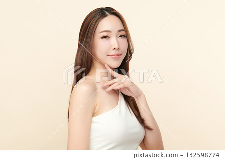 A beautiful young Asian woman with clean, fresh skin against a beige background. Skincare, facial treatment, cosmetology, beauty, and spa. An elegant portrait of an Asian woman. 132598774