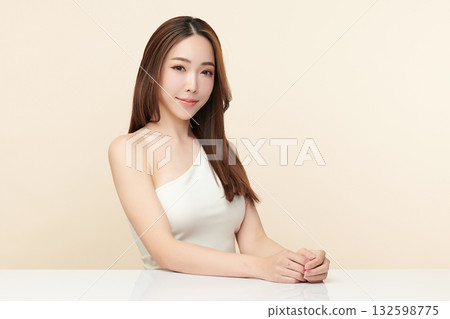 A beautiful young Asian woman with clean, fresh skin against a beige background. Skincare, facial treatment, cosmetology, beauty, and spa. An elegant portrait of an Asian woman. 132598775