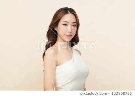 A beautiful young Asian woman with clean, fresh skin against a beige background. Skincare, facial treatment, cosmetology, beauty, and spa. An elegant portrait of an Asian woman. 132598782