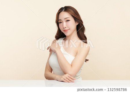 A beautiful young Asian woman with clean, fresh skin against a beige background. Skincare, facial treatment, cosmetology, beauty, and spa. An elegant portrait of an Asian woman. 132598786