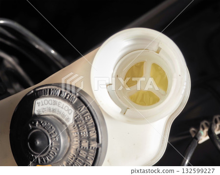 Close up of car brake fluid reservoir cap and fluid level Close up of car brake fluid reservoir cap and fluid level 132599227