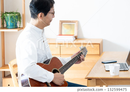 Middle-aged man playing guitar in the living room 132599475