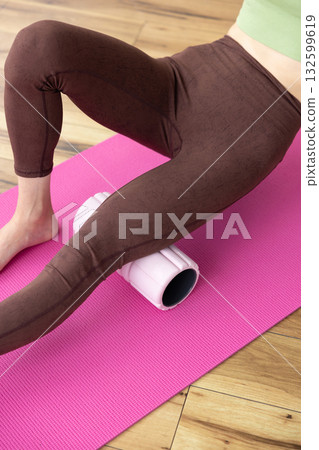 A woman uses a foam roller to massage her thighs A woman uses a foam roller to massage her thighs 132599619