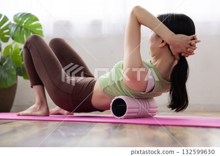 身穿瑜珈服的女子正用泡沫軸進行自我按摩 132599630