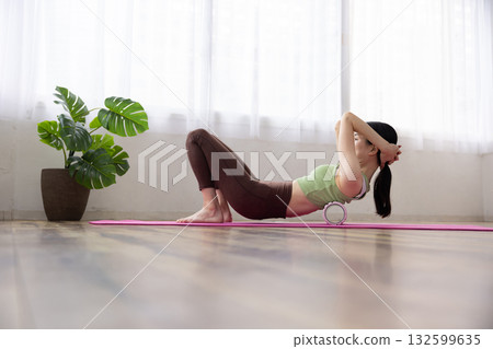 身穿瑜珈服的女子正用泡沫軸進行自我按摩 132599635