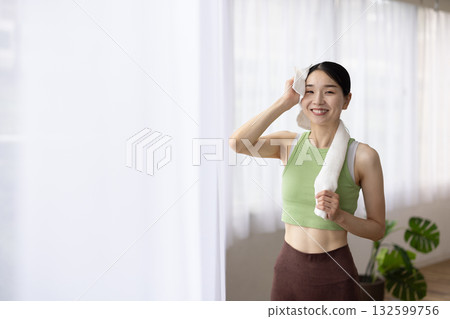 一位身穿瑜珈服的女子正在用毛巾擦汗 132599756