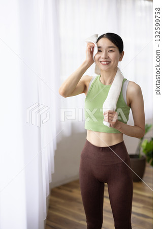 A woman in yoga wear wiping sweat with a towel A woman in yoga wear wiping sweat with a towel 132599758
