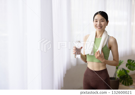 身穿瑜珈服、微笑的女子手裡拿著一瓶水 132600021