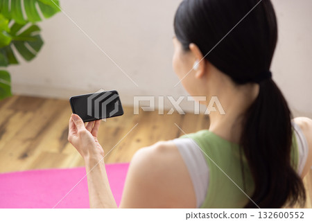 A woman wearing wireless earphones operates a smartphone 132600552