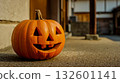 A jack-o-lantern sitting on the ground in front of a building 132601141