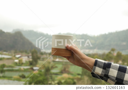 Person enjoys a warm drink while admiring the beautiful hills Person enjoys a warm drink while admiring the beautiful hills 132601163